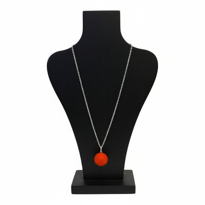 Hand felted orange wool ball necklace on a silver plated chain displayed on a black bust.