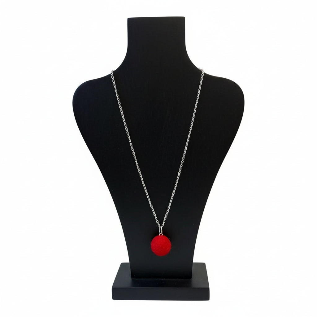Hand felted red wool ball pendant on a silver plated chain displayed on a black jewelry bust.