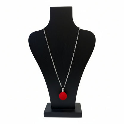 Hand felted red wool ball pendant on a silver plated chain displayed on a black jewelry bust.