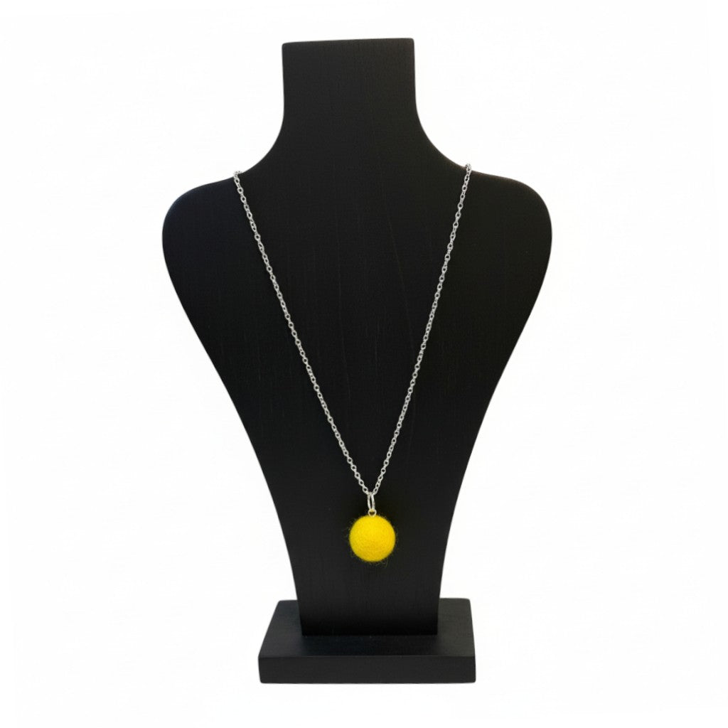 Hand felted yellow wool ball pendant on a silver plated chain displayed on a black bust.