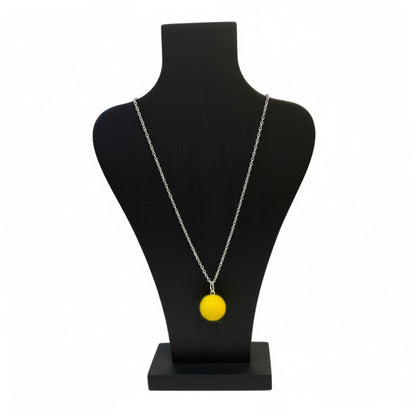 Hand felted yellow wool ball pendant on a silver plated chain displayed on a black bust.