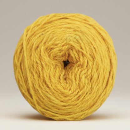 A round ball of golden yellow Uradale 100% Shetland wool yarn in the Tormentil colourway.